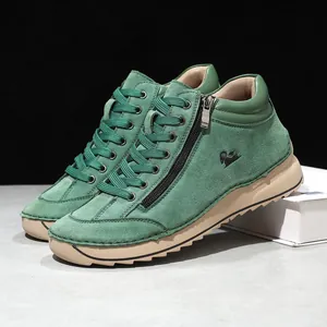Detail view of green suede high-top casual shoes with side zipper and soft tan sole
