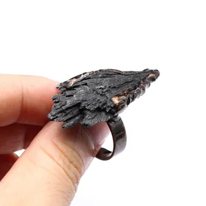 Dettaglio della consistenza naturale di una tormalina nera grezza su un anello vintage usurato.