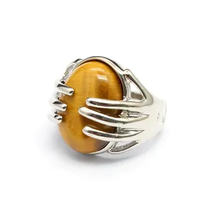 Macro view of hand-shaped silver ring setting holding an oval tiger eye gemstone