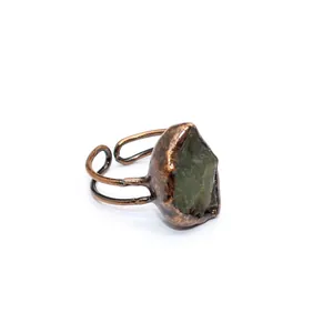 Dettaglio di un anello in bronzo stile medievale con una pietra naturale grezza verde.