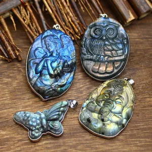 Close-up detail of carved natural labradorite pendants featuring owl and mermaid motifs