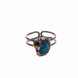 Primo piano di un anello in rame vintage con una pietra di cristallo blu naturale grezza.