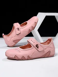 Pink leather Mary Jane shoes for women with adjustable Velcro strap and wavy sole design.
