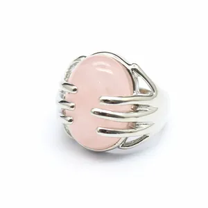 Detailed macro view of silver-toned ring with pink oval natural stone and hand-grip claw