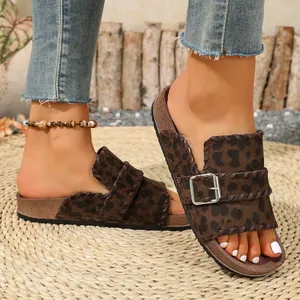 Close-up of women's leopard print slides with stylish metal buckle on woven mat