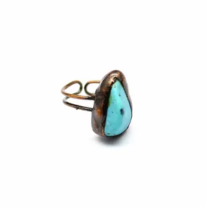 Dettaglio ravvicinato di un anello in rame stile medievale con pietra turchese grezza