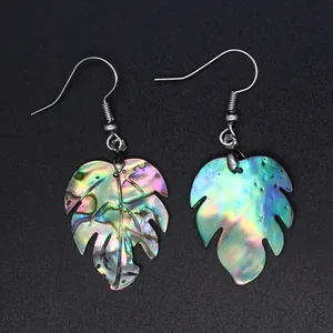 Vista detallada de los pendientes de concha de abulón con diseño de hoja de monstera tropical