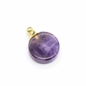Gros plan d'un pendentif flacon d'huile essentielle en améthyste violette ronde dorée