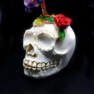 Detailansicht eines Kristall-Geldbaums auf einer Totenkopf-Basis mit roter Rosenverzierung.