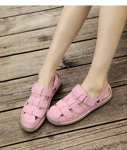 Close-up detail of stylish pink woven leather sandals for women worn on wood surface