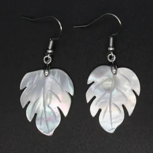 Primer plano de pendientes con forma de hoja de monstera en nácar blanco natural