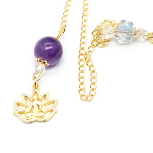 Detail view of golden lotus meditation pendant with purple bead and faceted crystal