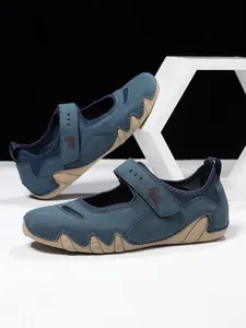 Detailed view of blue Mary Jane shoes featuring a Velcro strap and a wavy tan sole