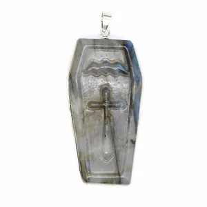 Close-up detail of a hand-carved cross on a natural labradorite coffin-shaped pendant