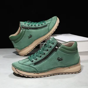 Detail view of green suede casual shoes featuring side zippers and thick tan soles.