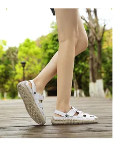 Close-up of stylish white leather summer sandals for women worn on a wooden path
