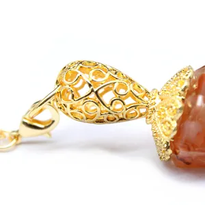 Macro view showing the intricate gold filigree cap on a red stone hexagonal pendulum