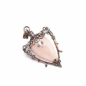 Detailed macro view of a vintage rose quartz pendant with ornate antique copper metalwork.