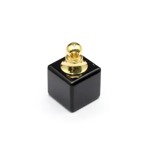 Gros plan d'un pendentif flacon d'huile essentielle en pierre noire carrée avec bouchon doré.