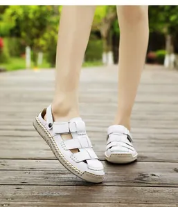 Close-up of stylish white women's summer sandals worn on a wooden walkway outdoors