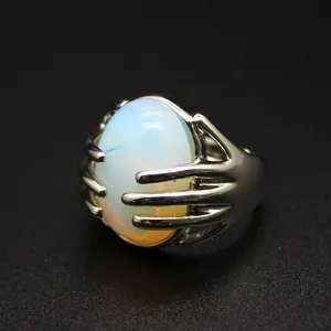 Close-up of a silver hand-shaped ring holding an oval opal-like natural stone