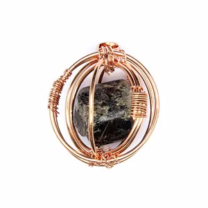 Dettaglio di un ciondolo artigianale in filo d'oro rosa con pietra naturale scura