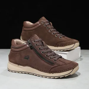 Close-up of brown suede ankle boots with hand-stitched detailing and side zipper.