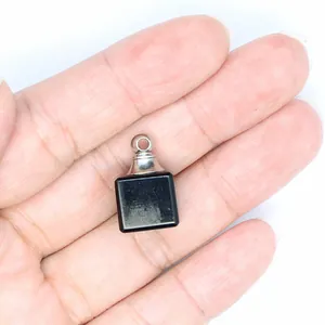 Gros plan d'un petit pendentif flacon d'huile essentielle en pierre noire tenu en main