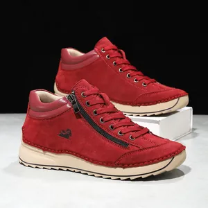 Close-up of red suede leisure shoes with side zipper and hand-stitched detailing.