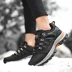 Close-up of black and orange low-top hiking shoes worn in the snow.