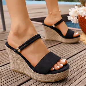 Gros plan sur des sandales compensées noires avec texture paille et deux brides