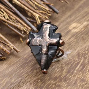 Détail d'une bague en obsidienne en forme de pointe de flèche avec croix en bronze