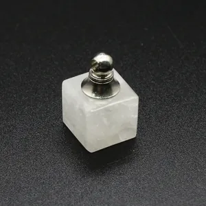 Gros plan d'un pendentif flacon de parfum carré en cristal blanc avec bouchon en métal