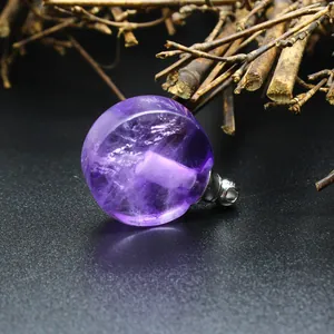 Gros plan d'un pendentif flacon d'huile essentielle en améthyste naturelle sur fond noir