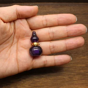 Detailed view of a small purple fluorite gourd perfume bottle pendant on a human hand