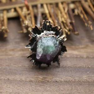 Gros plan d'une bague médiévale vintage avec une pierre brute de fluorite verte et violette.
