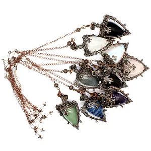 Macro view of various teardrop-shaped natural stone pendants with vintage bronze filigree.