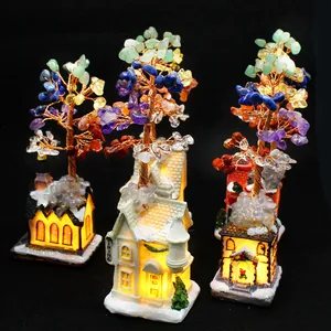 Detailed macro view of hand-woven crystal chakra trees atop glowing miniature decorative houses