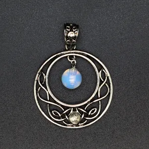 Detail of a vintage silver circular moon pendant with an intricate hollow knotwork design.