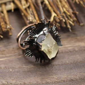 Gros plan d'une bague médiévale vintage avec cristal brut et design en métal texturé.