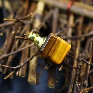 Gros plan du pendentif flacon d'huile essentielle en pierre d'œil de tigre carrée