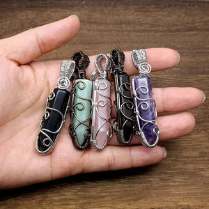 Close-up detail of handcrafted wire-wrapped hexagonal crystal pendants held in a hand.