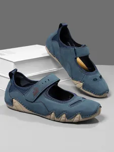 Detail view of blue Mary Jane sport shoes with unique wavy soles and hook and loop closure.