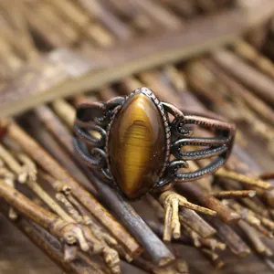 Vista macro ravvicinata di un anello traforato in bronzo antico con pietra occhio di tigre