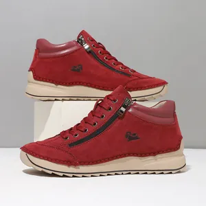 Detailed view of red suede high-top casual shoes with hand-stitched soft flat soles.