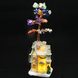 Close-up detail of a handmade 7 chakra crystal tree on a decorative glowing house base