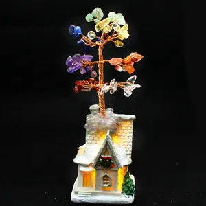 Multi-colored chakra gemstone crystal money tree on warm glowing LED snow cottage.