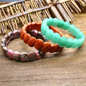 Detail of three natural faceted stone bracelets in green and orange tones on wood.