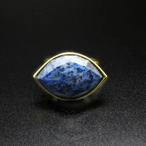 Detail view of an elegant gold ring with a large faceted blue marquise-cut gemstone