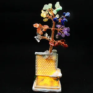 Detailed view of a handmade 7 chakra crystal tree ornament on a glowing small house base